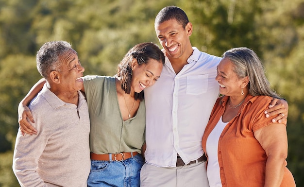 Feliz abrazo y sonrisa a una familia adulta en un parque de pie juntos Madre padre niños adultos riendo Felicidad amor y naturaleza hombre y mujer con pareja mayor en la naturaleza en un evento al aire libre