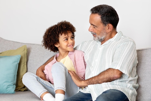 Feliz abuelo hispano con su nieto abrazándose en casa