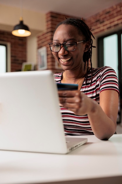 Feliz adicto a las compras haciendo compras en la venta de tiendas de Internet, con tarjeta de crédito, pago en línea, compras minoristas electrónicas. Persona sonriente que compra productos de forma remota usando una computadora portátil, el comprador paga el pedido