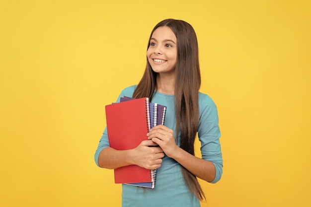 Feliz adolescente con cuaderno escolar para hacer notas educativas