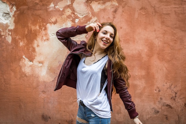 Feliz adolescente disfrutando y bailando con un fondo de pared roja con espacio de copia