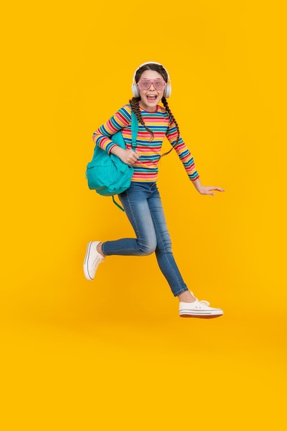 Feliz adolescente enérgica pulando depois da escola escola de fundo amarelo De volta à escola