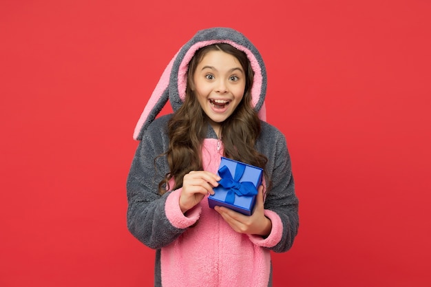 Feliz adolescente usa pijamas kigurumi de conejo divertido y caja de regalo, viernes negro.
