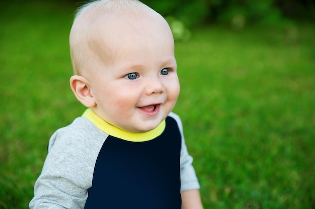 Feliz y adorable bebé sentado en el césped y riendo en un día de verano Sonrisa feliz de 8 meses