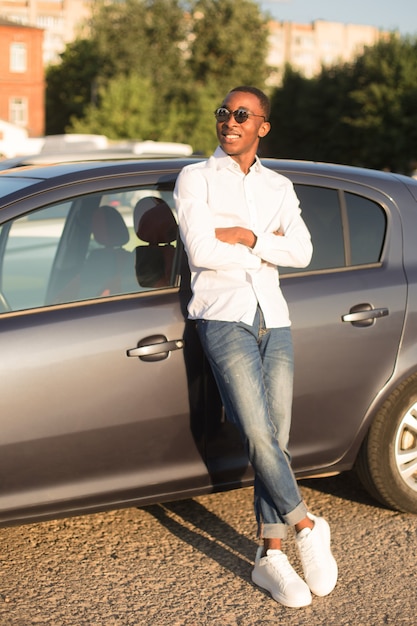 Feliz afroamericano junto a un coche en verano