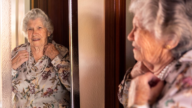 Feliz y alegre abuela caucásica de los 90 con ropa elegante mirando al espejo