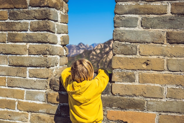 Feliz alegre alegre niño turista en la gran muralla china divirtiéndose en viajes sonriendo riendo y