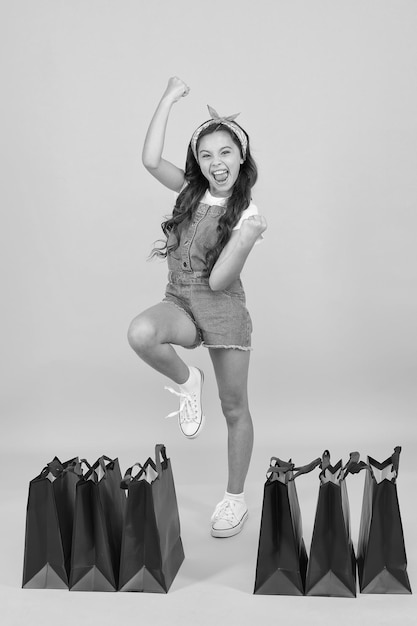 Feliz alegre Chica de compras Tienda de moda Niña con paquetes de compras Niño feliz en la tienda con bolsas Niño pequeño en estilo de verano Ventas de temporada Venta de verano Día de compras Boutique de moda