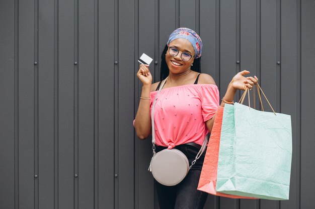 Feliz americana africano jovem segurando sacolas de compras e cartão de crédito