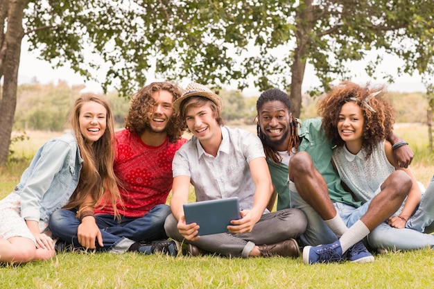 Feliz amigos no parque olhando tablet