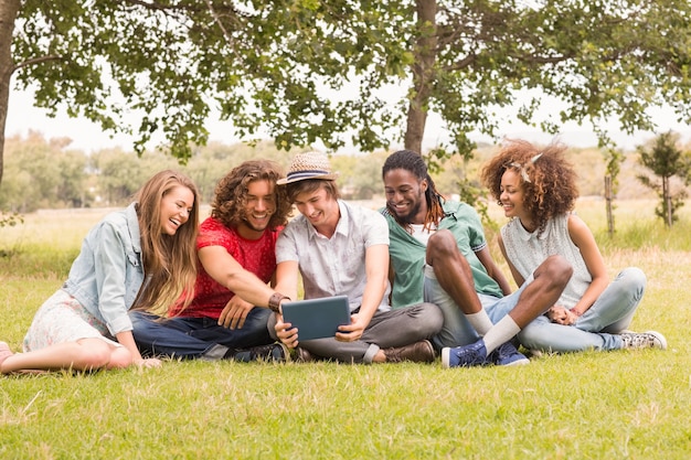 Feliz amigos no parque olhando tablet