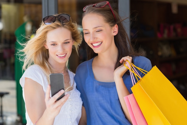 Feliz amigos sorridentes olhando para o smartphone