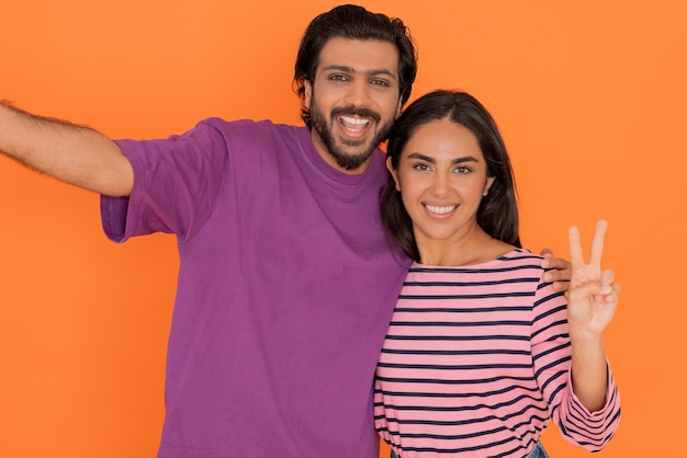 Foto feliz amorosa pareja joven oriental tomando selfie juntos en naranja