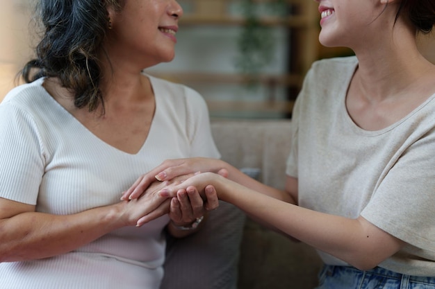 Feliz anciana asiática y su hija adulta se abrazan en el sofá