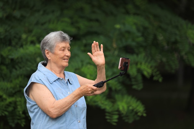 Feliz anciana discapacitada al aire libre en el parque de verano y hablando por teléfono