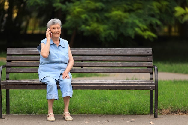 Feliz anciana discapacitada sentada en un banco al aire libre en el parque