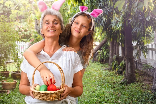 Feliz anciana y jovencita con huevos de pascua en canasta al aire libre