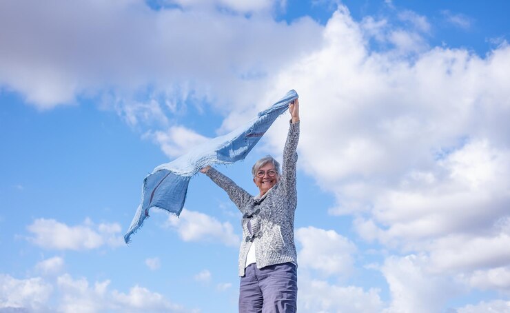 Feliz anciana madura al aire libre ondeando bufanda en el viento Sonriente anciana caucásica con el pelo corto con gafas disfrutando de la libertad y las vacaciones