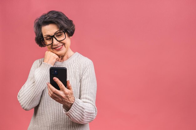 Foto feliz anciana madura sosteniendo un teléfono inteligente usando aplicaciones móviles en línea sonriendo