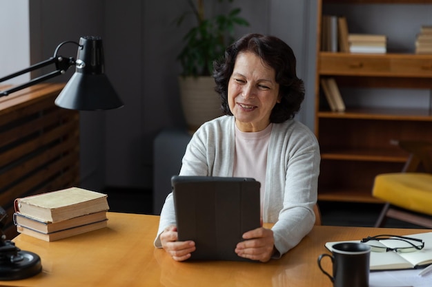 Feliz anciana de mediana edad sosteniendo tablet hablar en videollamada con amigos familia riendo madura