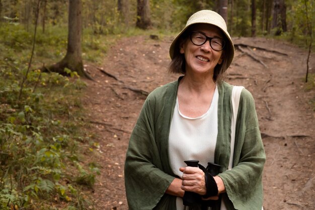 Feliz anciana sonriente tomando un descanso durante la caminata nórdica en el bosque de verano