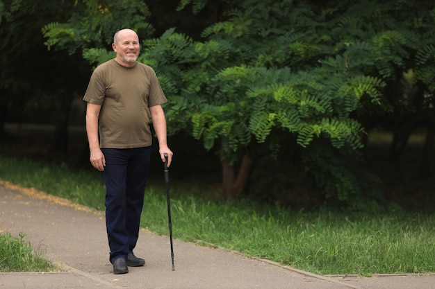 Feliz anciano discapacitado caminando con bastón al aire libre en verano