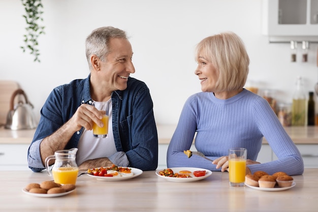 Feliz anciano y mujer desayunando en casa charlando