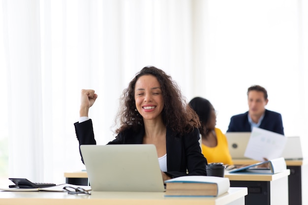 Feliz animado bem sucedido Linda hispânica empresária triunfando no escritório moderno com laptop, pose de feliz sucesso. Trabalho a partir de casa