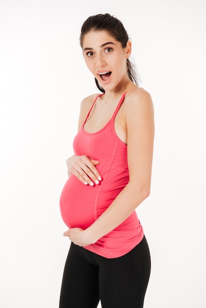 Feliz animado jovem mulher grávida segurando a barriga