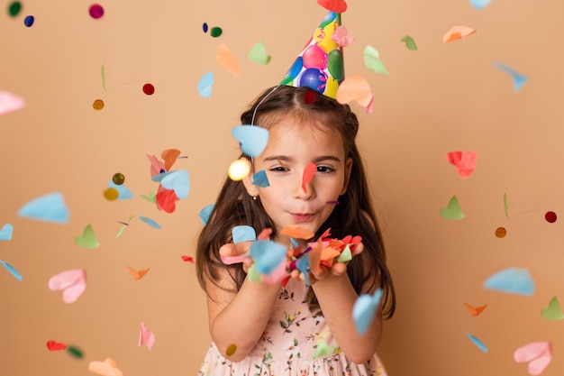 Feliz aniversário criança menina com confete em fundo bege