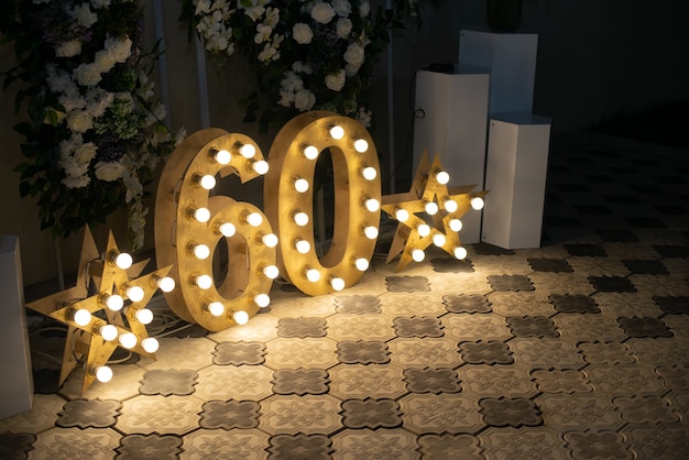 Foto feliz aniversário! decoração de interiores do aniversário de 60 anos. luzes da estrela. números 60 esculpidos em madeira com luz.