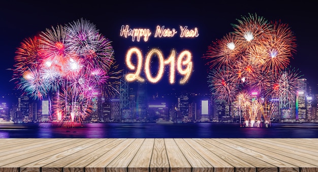 Feliz ano novo 2019 fogos de artifício sobre a paisagem urbana à noite com a tabela de prancha de madeira vazia