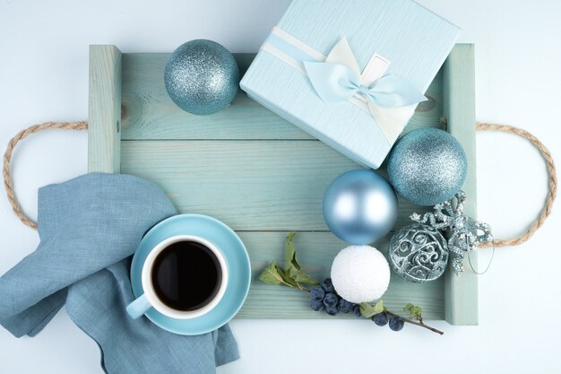 Feliz ano novo 2021, composição festiva com uma xícara de café, caixa de presente, balões de natal e uma bandeja em azul suave