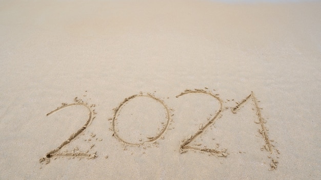 Feliz ano novo 2021 texto na praia, mensagem de 2021 anos escrito à mão na areia na bela praia copie o espaço no fundo da praia. conceito de ano novo.