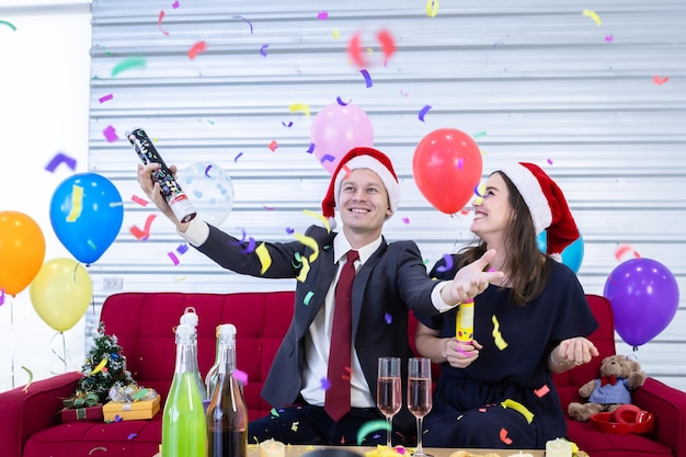 Feliz ano novo 2022 conceito, Casal feliz acendendo fogos de artifício de papel Com champanhe e biscoitos na mesa na festa de Natal e Réveillon Depois de terminar o trabalho de negócios.
