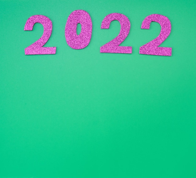 Foto feliz ano novo 2022 fundo cartão de férias de ano novo em números de rosa brilhante de fundo verde.