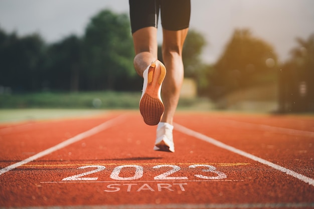 Feliz ano novo 2023 Corredor do homem do esporte correndo para o ano novo 2023 Início de sapatos de pé próximos correndo no estádio ir para Objetivo do sucesso Pessoas correndo como parte do número 2023 Cuidados de saúde esportivos