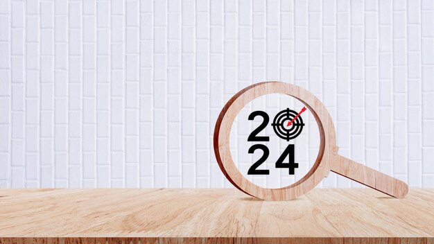 Feliz ano novo 2024 com banner de conceito de negócio número de ano 2024 com ícone de alvo dentro da lupa de madeira em fundo de mesa de madeira Planejamento para objetivos e conceitos de sucesso