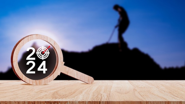 Feliz ano novo 2024 com banner de conceito de negócio número de ano 2024 com ícone de alvo dentro da lupa de madeira em fundo de mesa de madeira Planejamento para objetivos e conceitos de sucesso