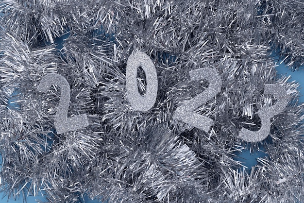 Feliz ano novo com números 2023 e ornamentos festivos de glitter prateado sobre fundo azul. Postura plana,