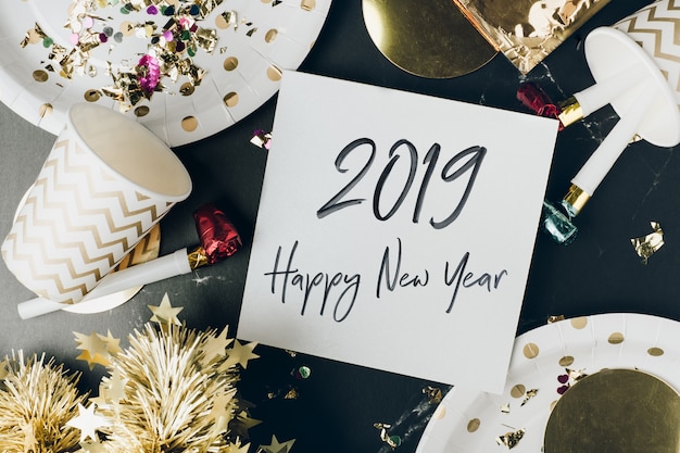 Feliz año nuevo 2019 en tarjeta de felicitación en mesa de mármol con taza de fiesta