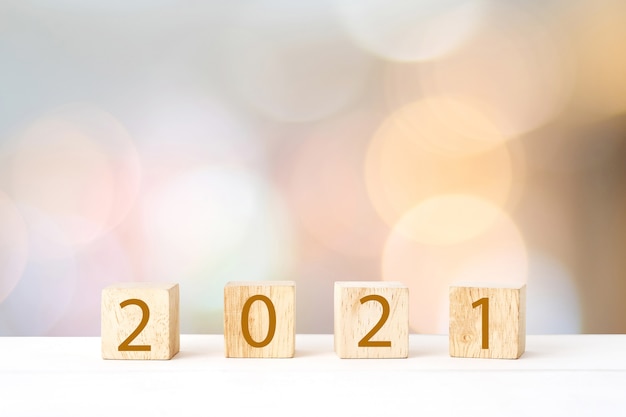 Feliz año nuevo 2021 en bloque de cubo de madera y desenfoque de luz bokeh abstracta