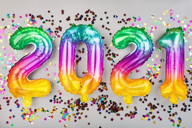 Foto feliz año nuevo 2021 fondo. globos metálicos colores del arco iris en blanco. endecha plana, vista superior