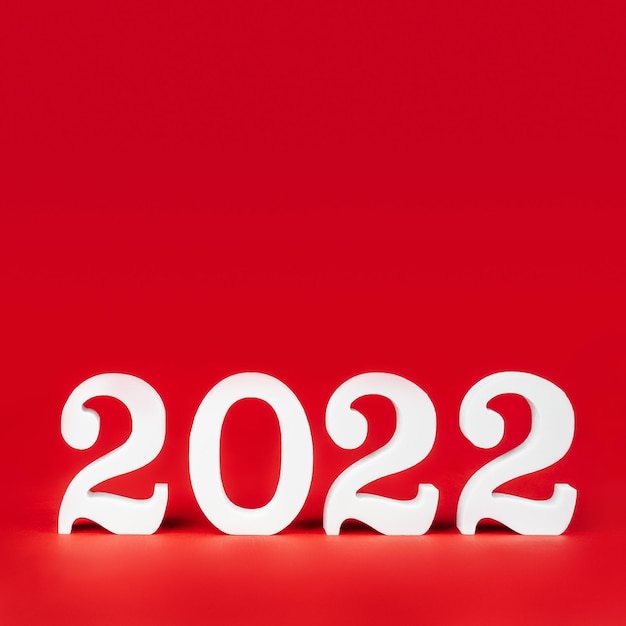 Feliz año nuevo 2022. Banner cuadrado rojo brillante con números de madera blancos 2022 de pie en la parte inferior. Feliz Navidad. Copie el espacio. Lugar para el texto