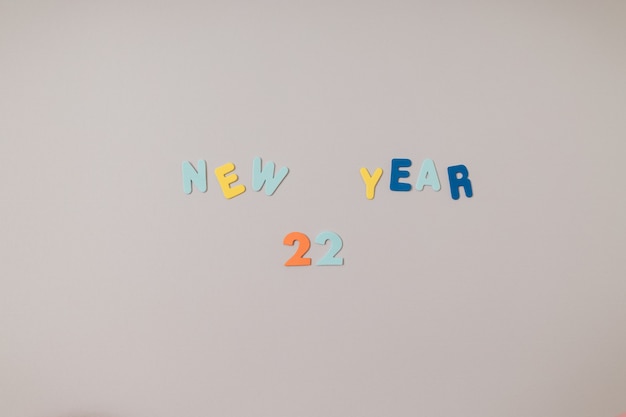 Feliz año nuevo 2022 escrito con velas de colores y letras adhesivas de espuma sobre un fondo gris y morado. Copie el espacio, endecha plana.
