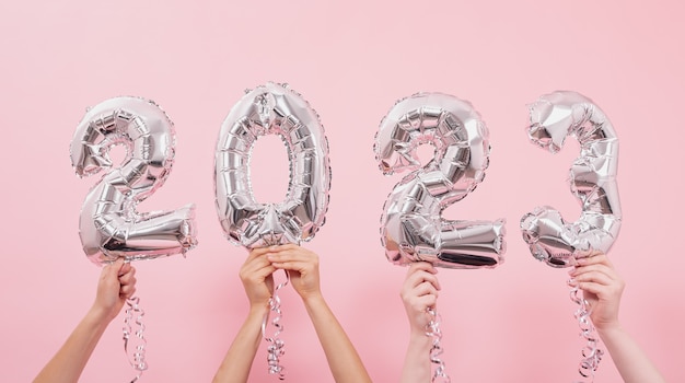 Feliz año nuevo 2023 celebración. Globos de lámina de plata numeral 2023 sobre fondo rosa.