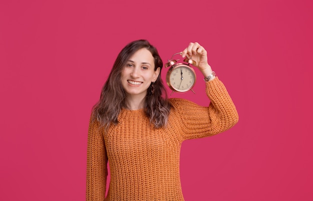 Feliz año nuevo, alegre joven sosteniendo despertador sobre espacio rosa