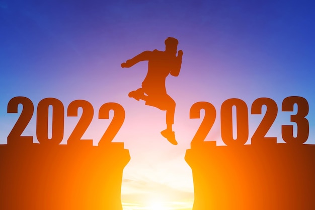 Feliz Año Nuevo Números 2023 Silueta un hombre guapo saltando se siente feliz moviéndose mañana 2022 a 2023 amanecer sobre el fondo del horizonte Concepto de salud y feliz año nuevo