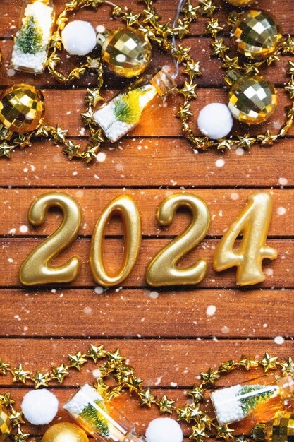 Foto feliz año nuevo números de madera 2024 en un acogedor fondo de madera marrón festivo con lentejuelas de nieve