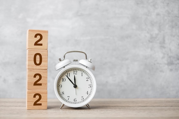 Feliz año nuevo con reloj despertador vintage y bloque 2022. Navidad, nuevo comienzo, resolución, cuenta atrás, metas, plan, acción y concepto de motivación